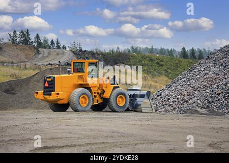 Chargeur sur pneus jaune devant un tas de rochers sur le chantier de construction sur une belle journée, espace de copie, pas de logos, pas de personnes, photographié de la voie publique Banque D'Images