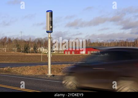 Voiture approchant une caméra de vitesse en bord de route sur une journée ensoleillée de l'hiver. Exposition prolongée pour rendre le véhicule flou Banque D'Images