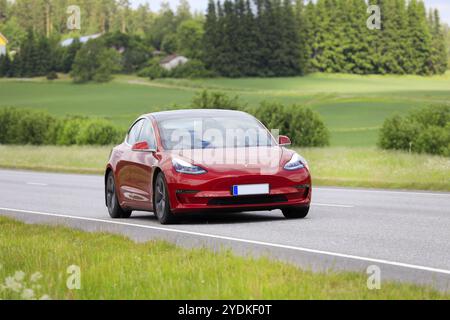 Red Tesla Model 3 berline voiture électrique année 2020 à grande vitesse sur l'autoroute. Salo, Finlande. 23 juin 2022 Banque D'Images