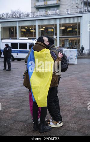 24.02.2023, Berlin, Allemagne, Europe, trois participants se tiennent fermement embrassés devant le Café Moskau, qui a été brièvement rebaptisé Café Kiev, devant o Banque D'Images