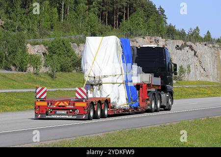 La semi-remorque noire Volvo FH transporte un objet industriel comme charge surdimensionnée le long de l'autoroute par une journée ensoleillée, vue arrière. Paimio, Finlande, 18 mai 2018, Europe Banque D'Images