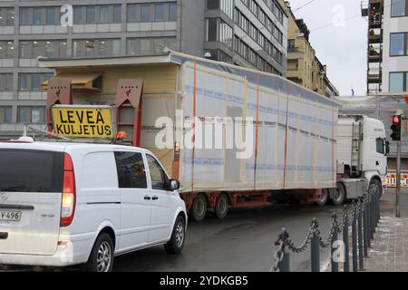 HELSINKI, FINLANDE, le 16 JANVIER 2017 : le véhicule d'escorte aide au transport de grandes charges surdimensionnées du module de maison préfabriqué temporaire dans un virage étroit à droite Banque D'Images