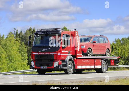 Camion de remorquage à plateau Red Volvo FL Redgo transporte une voiture rouge le long de l'autoroute 2 par une journée ensoleillée. 9 juin 2023 Banque D'Images