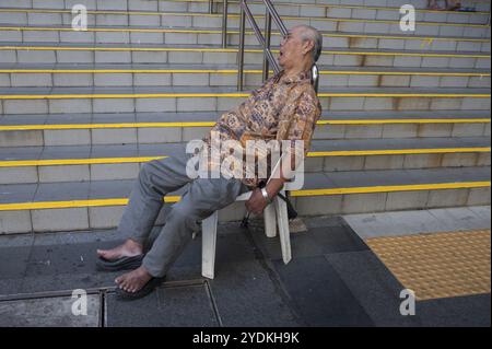 17.12.2017, Singapour, République de Singapour, Asie, un vieil homme est assis sur une chaise à Crete Ayer Square, à côté du Temple de relique des dents de Bouddha à Sing Banque D'Images