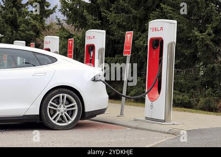 Vue latérale de la voiture électrique Tesla Model S blanche connectée et en charge à la station Supercharger un jour de printemps à Paimio, Finlande, le 28 avril, 2 Banque D'Images