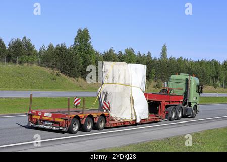 Green Scania semi-remorque transporte un objet industriel couvert de bâche comme charge longue sur l'autoroute d'été par une journée ensoleillée. Vue latérale. Salo, Finlande, 18 mai, 2 Banque D'Images