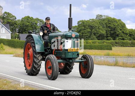 Kimito, Finlande. 6 juillet 2019. Tracteur Bolinder-Munktell année 1956 et pilote sur Kimito Traktorkavalkad, exposition annuelle de tracteurs vintage et parade Banque D'Images