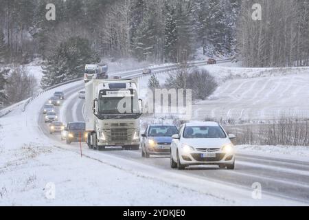 Circulation routière à deux voies à travers les paysages ruraux dans les chutes de neige hivernales avec voitures et camions alignés. Salo, Finlande. 28 décembre 2021 Banque D'Images