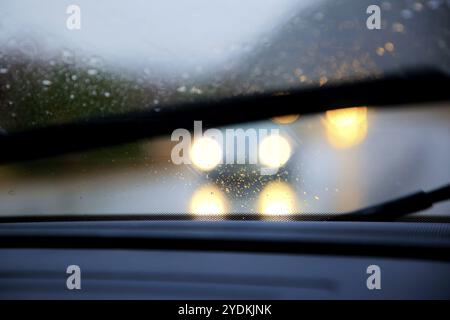 Conduite sur autoroute par forte pluie, essuie-glaces activés, faible visibilité avec phares éblouissants des véhicules venant en sens inverse Banque D'Images