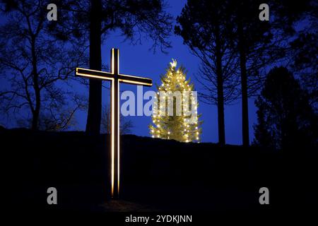 Croix illuminée et arbre de noël avec des lumières vives dans l'heure bleue du matin à Noël. Salo, Finlande. 2020 Banque D'Images