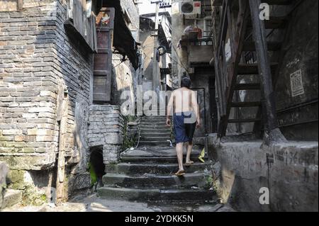 04/08/2012, Chongqing, Chine, Asie, Un homme grimpant un vieil escalier en pierre dans la zone des dix-huit escaliers, devant des maisons traditionnelles dans la vieille ville de la Banque D'Images