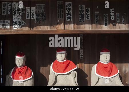 29.12.2017, Takayama, Gifu, Japon, Asie, une rangée de statues Jizo en pierre, recouvertes de bonnets et de bavoirs rouges, se trouve sous un auvent en bois sur le terrain de HID Banque D'Images