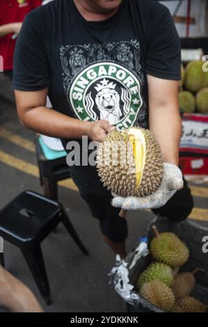 24/02/2019, Singapour, République de Singapour, Asie, Un vendeur ouvre un durian frais avec un couteau dans un marché de rue à Chinatown, en Asie Banque D'Images