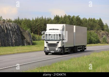 Un gros camion de fret blanc transporte des marchandises le long de l'autoroute par une belle journée d'été. Véhicule : aucun logo visible Banque D'Images