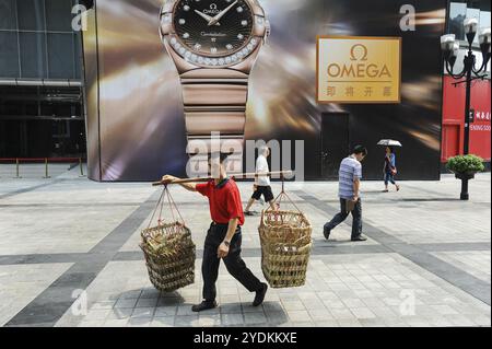 04.08.2012, Chongqing, Chine, Asie, Un porteur, aussi appelé bang-bang man, porte un poteau en bambou avec des paniers vides pour les marchandises sur son épaule pendant la marche Banque D'Images