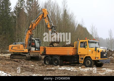 FORSSA, FINLANDE, le 28 JANVIER 2017 : la pelle sur chenilles Liebherr R 918 charge le sol sur le tombereau basculant Sisu SR332 jaune en hiver Banque D'Images