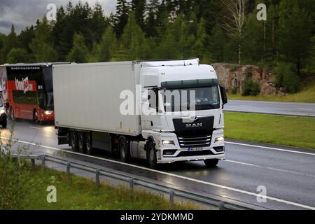 Nouveau camion TGX 18,510 homme blanc devant le camion semi-remorque FRC dans le trafic autoroutier un matin pluvieux d'automne. Salo, Finlande. 27 août 2021 Banque D'Images