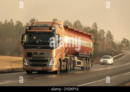 KAARINA, FINLANDE, 5 DÉCEMBRE 2016 : camion de transport en vrac orange Volvo FH sur la route à l'arrivée de la tempête de neige hivernale dans la lumière du coucher du soleil de l'après-midi Banque D'Images