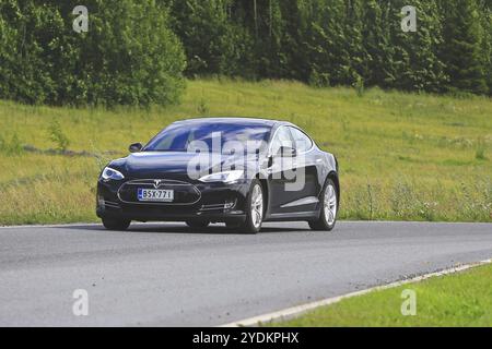 PAIMIO, FINLANDE, 17 JUILLET 2016 : le véhicule électrique Tesla Model S noir se déplace sur la route rurale à travers la nature finlandaise verte en été Banque D'Images