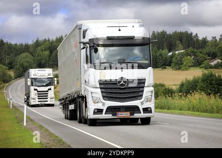 Deux camions lourds blancs, Mercedes-Benz Actros et Scania, tirent des semi-remorques sur l'autoroute un jour d'été. Salo, Finlande. 25 août 2022 Banque D'Images