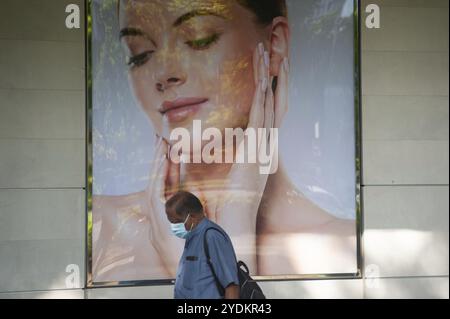 28.05.2020, Singapour, République de Singapour, Asie, Un homme passe devant un espace publicitaire pendant le confinement portant un masque facial pour se protéger Banque D'Images