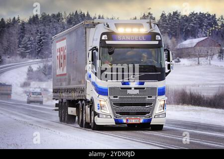 Bleu blanc Volvo FH semi-remorque camion Kuljetusliike Harri Sandell Oy avec des phares lumineux sur la route 52 au crépuscule d'hiver. Salo, Finlande. 27 décembre 2021 Banque D'Images