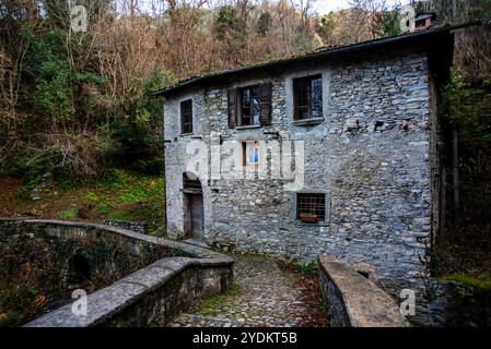 Ancien moulin abandonné sur les rives d'un ruisseau de montagne avec vieille pointe de pierre parmi les bois alpins près de Varenna sur le lac de Côme en Italie Banque D'Images