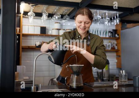 Les mains du barista versent de l'eau bouillante dans la cafetière filtre Banque D'Images