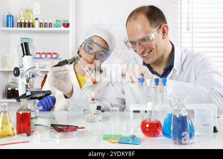 Un jeune scientifique dirige une classe de maître en chimie pour une petite fille dans un laboratoire chimique Banque D'Images