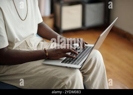 Jeune homme tapant sur ordinateur portable dans un cadre confortable Banque D'Images