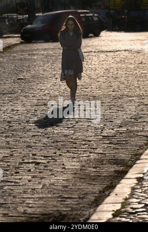 Triste jeune femme se promène dans ses bras dans la rue pavée en contre-jour du bazar Tesnjar dans la ville de Valjevo, en Serbie Banque D'Images