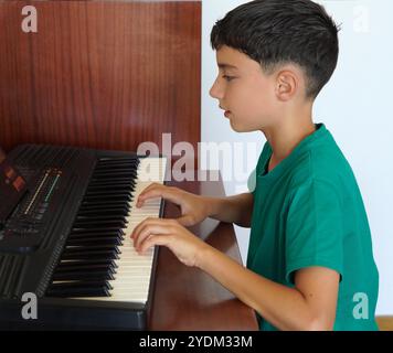 enfant de préadolescence utilisant l'application et la tablette pour apprendre à jouer du clavier ou du piano Banque D'Images