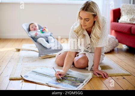 Mère regardant la propriété dans le papier avec bébé en arrière-plan Banque D'Images