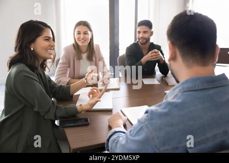 Joyeuse jeune femme latino chef d'entreprise riant à la réunion de groupe Banque D'Images