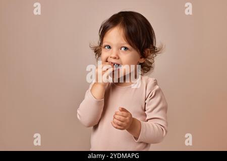 fille d'enfant souriante tenant pastille de fruits sur fond beige. alimentation saine pour bébé. Banque D'Images