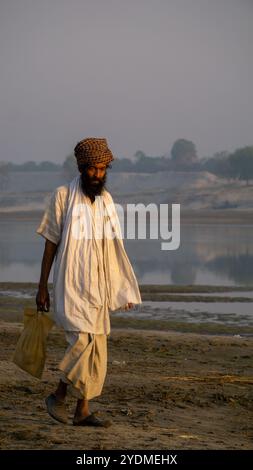 Lumière du soleil du matin sur un beau fond naturel. Un homme baul marche le long de la rive de la rivière. C'est une belle scène d'un doux matin sur la rive Banque D'Images