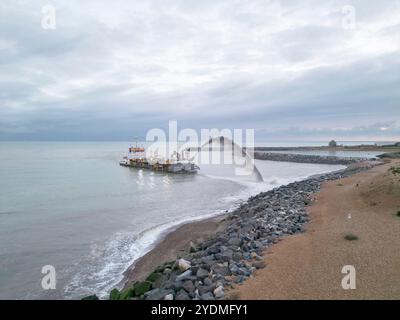 chaland de drague pulvérisant du gravier sur la plage du port souverain d'eastbourne pour remplacer le gravier perdu Banque D'Images