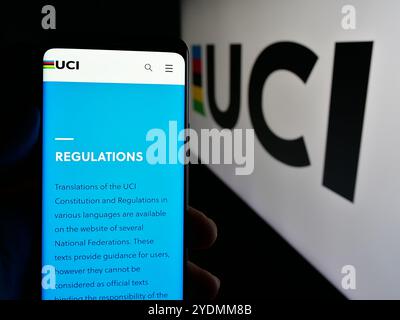 Personne tenant un téléphone portable avec la page web de l'Union cycliste internationale (UCI) sur l'écran devant le logo. Concentrez-vous sur le centre de l'écran du téléphone. Banque D'Images