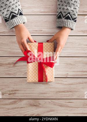 Les mains de la femme donnent cadeau de noël dans la boîte de cadeau Banque D'Images
