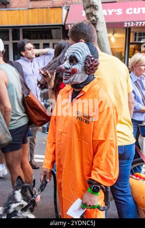 Personne dans un masque de clown effrayant se tient dans une rue animée de New york pendant un festival ou une parade de chien avec des gens en arrière-plan Banque D'Images