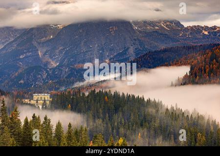 Matin lumière d'automne et couleurs avec nuages bas et brouillard dans la vallée dans les Dolomites avec vue vers le grand bâtiment de l'Institut Pie Banque D'Images