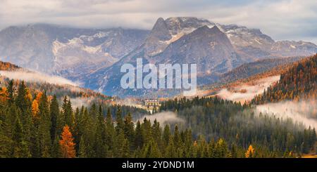 Une large image panoramique 2:1 avec la lumière d'automne du matin et les couleurs avec les nuages bas et le brouillard dans la vallée dans les Dolomites avec vue vers le L. Banque D'Images