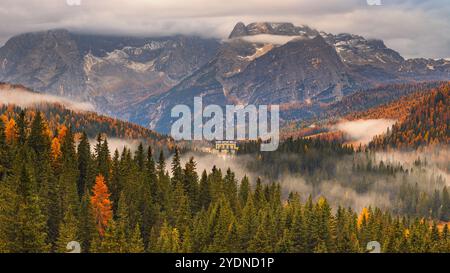 Matin lumière d'automne et couleurs avec nuages bas et brouillard dans la vallée dans les Dolomites avec vue vers le grand bâtiment de l'Institut Pie Banque D'Images