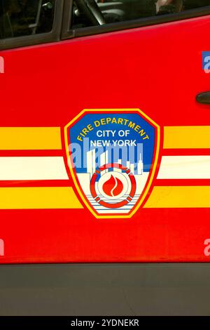 Gros plan de l'emblème des pompiers de la ville de New York sur un véhicule d'urgence rouge avec des bandes jaunes audacieuses. Logo FDNY Banque D'Images