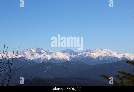 Rochers enneigés et montagnes couvertes d'arbres et collines du Caucase contre un ciel bleu clair, vue depuis une plate-forme d'observation sur les collines Banque D'Images