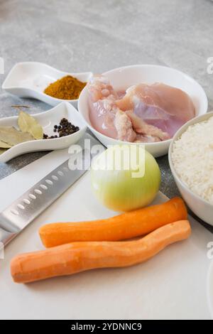 Une planche à découper magnifiquement agencée avec un assortiment de bols remplis de délicieux poulet, de carottes vibrantes, d'oignons aromatiques, de riz moelleux, d'un Banque D'Images