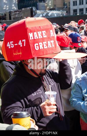 New York, NY, États-Unis. 27 octobre 2024. Des foules de partisans de Donald Trump, dont beaucoup portent des casquettes et des chemises de marque MAGA ou Trump, se rassemblent devant Madison Square Garden avant un rassemblement en soirée. Un homme porte une énorme casquette rouge MAGA. Crédit : Ed Lefkowicz/Alamy Live News Banque D'Images