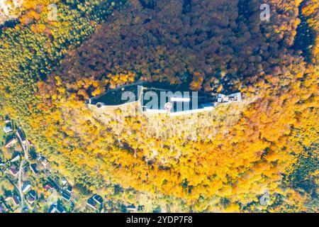 La vue aérienne capture le château médiéval de Bezdez niché au milieu des couleurs vibrantes de l'automne. Les arbres environnants présentent des teintes riches, créant un contraste saisissant avec la structure historique. Banque D'Images