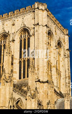 Une vue rapprochée de l'extérieur d'une cathédrale en pierre, mettant en valeur une tour haute et étroite avec des arches gothiques ornées et des fenêtres. Le bâtiment est construit Banque D'Images