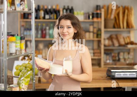 Jeune femme inspectant les fromages emballés dans l'épicerie Banque D'Images